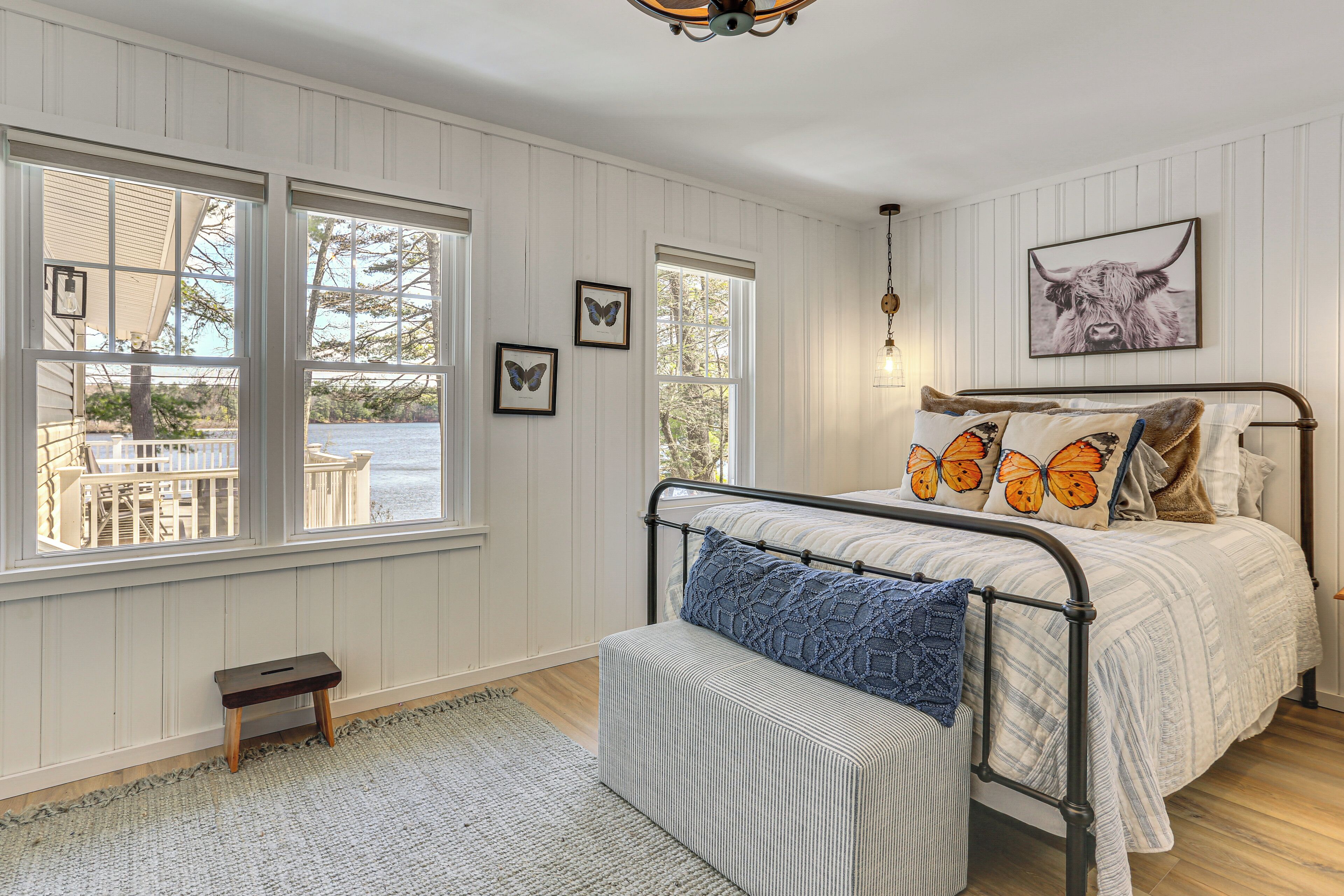 A bedroom with a bed, a bench, and a view of the outdoors.