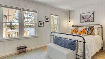 A bedroom with a bed, a bench, and a view of the outdoors.