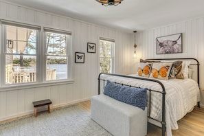 A bedroom with a bed, a bench, and a view of the outdoors. - A-frame Waterfront Escape on Lochada Lake (Glen Spey)