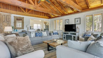 A spacious living area with a high ceiling, a television, and a fireplace.