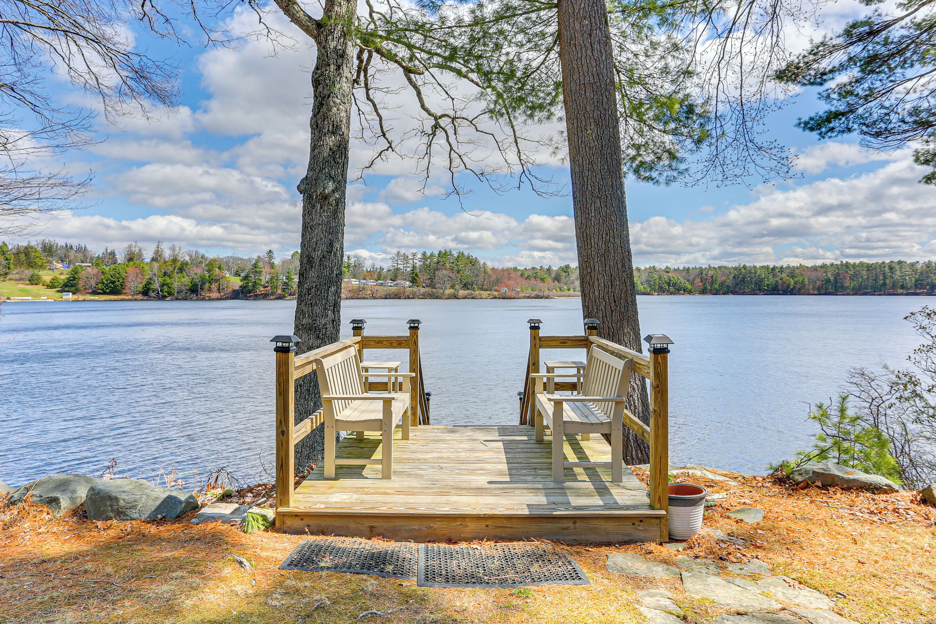 A wooden deck with two chairs and a metal trash can.