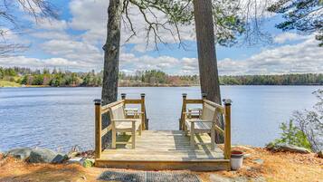 A wooden deck with two chairs and a metal trash can.