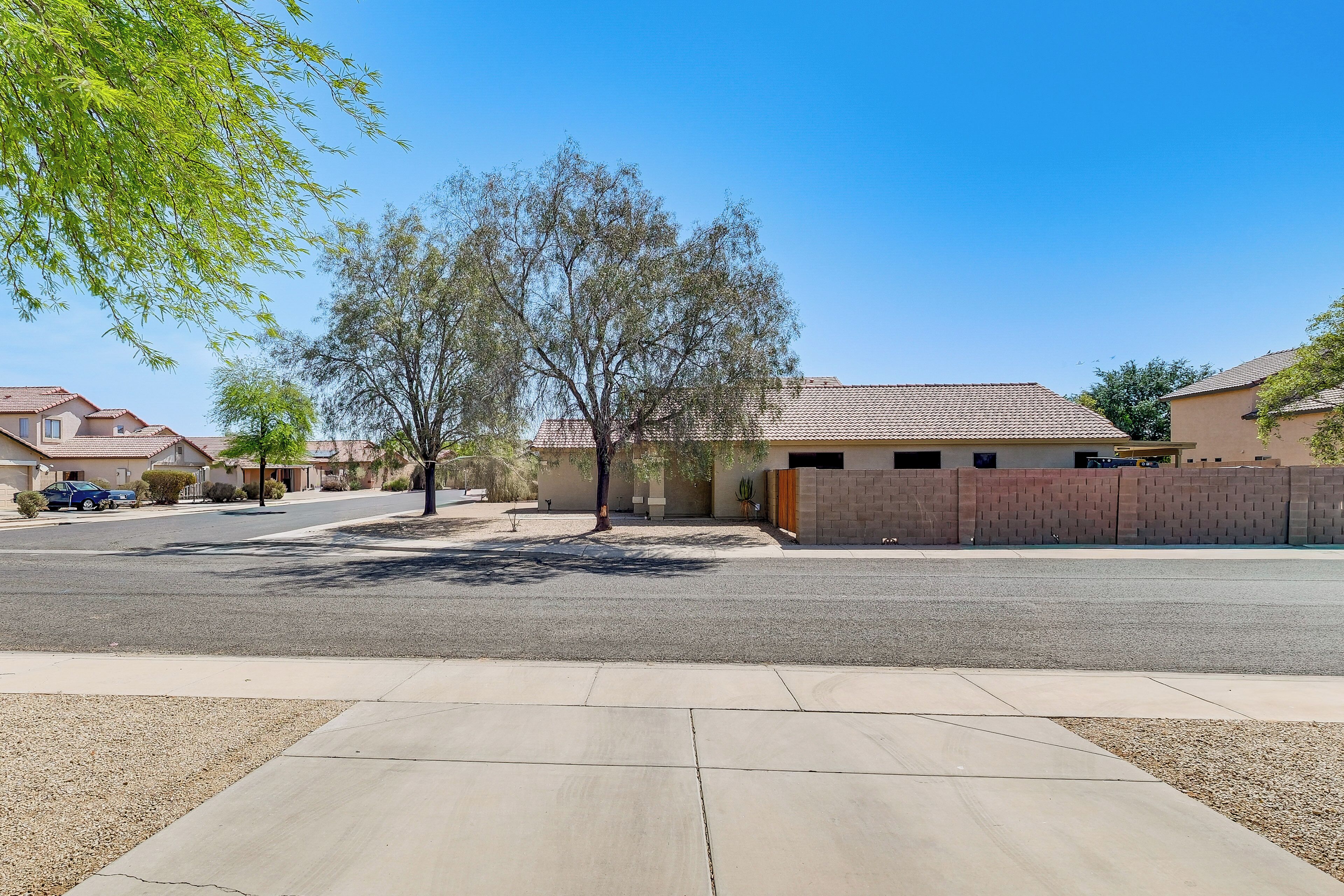 A residential street with houses, a tree, and a clear sky.
