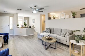 A modern living room with a grey sofa, a round coffee table, and a ceiling fan.