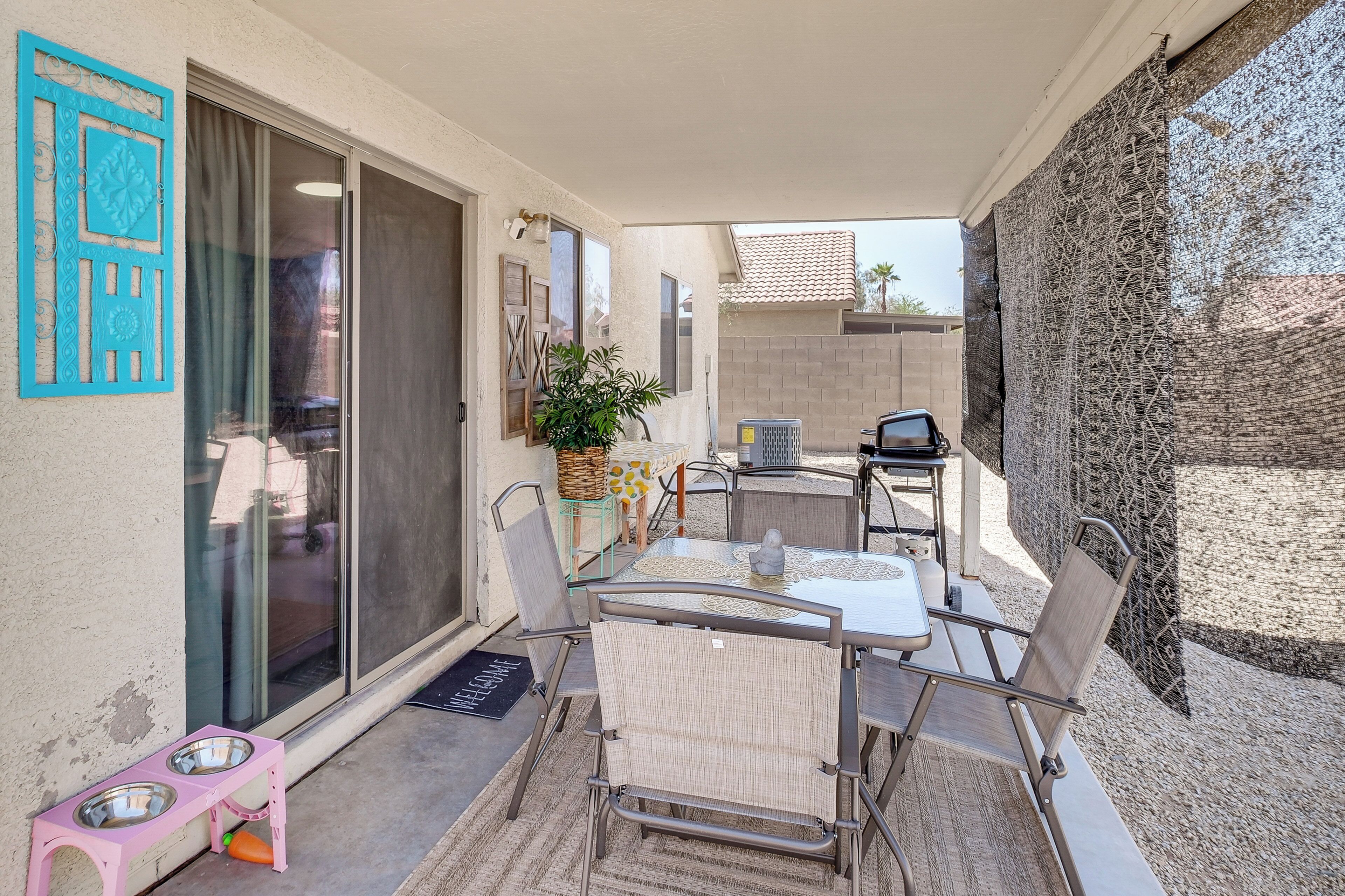 A patio with a table and chairs, a small pet feeding station, and a sliding glass door.