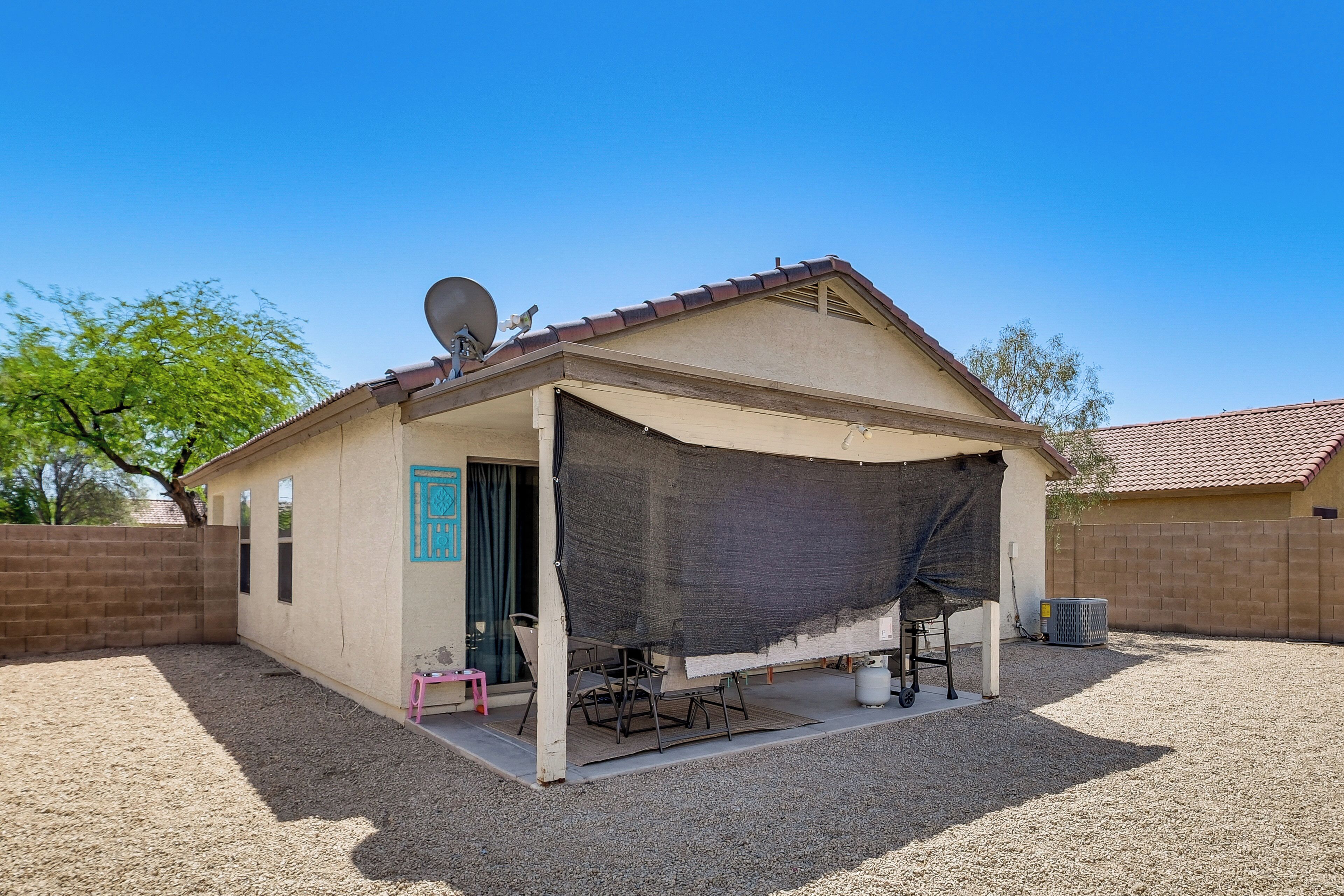 Una piccola casa con patio coperto, antenna parabolica e vialetto sterrato.