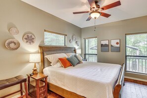 A bedroom with a bed, bedside table, lamp, and a ceiling fan.