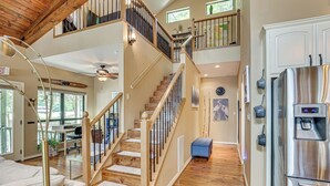 A spacious interior with a wooden staircase, a stainless steel refrigerator, and a dining area with a view. - Lakefront Winnsboro Home w/ 20+ Acres! (Winnsboro)