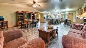 A spacious living room with a wooden floor, a ceiling fan, and a dining area with a bar. - Walk to Lake Texoma: Family Home w/ Fire Pit! (Kingston)