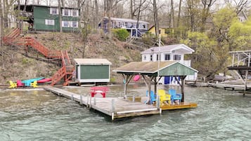 A dock with a small structure, a staircase, and a row of colorful Adirondack chairs.