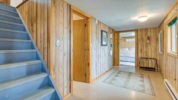 A wooden interior with a blue staircase, a door leading to another room, and a fire extinguisher on the wall.