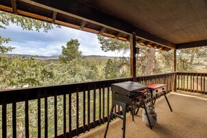 Un patio exterior con una parrilla y tanque de propano, con vistas a un paisaje boscoso.