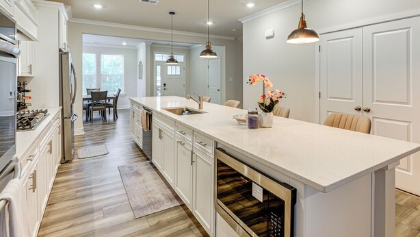 A modern kitchen with white cabinetry, stainless steel appliances, and pendant lighting.