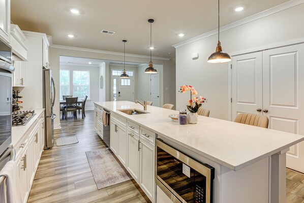 A modern kitchen with white cabinetry, stainless steel appliances, and pendant lighting.