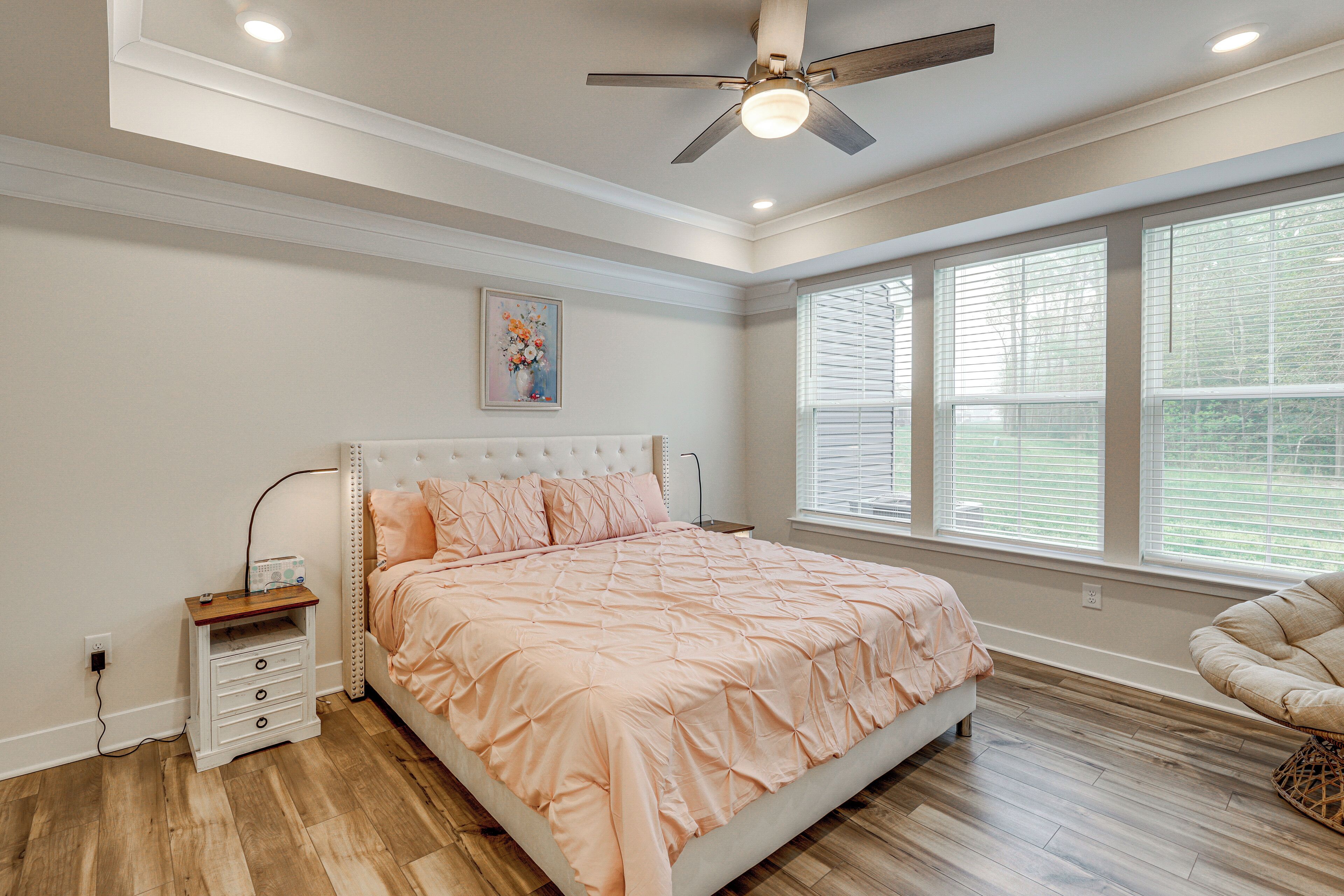 Quarto com cama, mesa de cabeceira e ventoinha no teto.