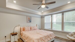 A bedroom with a bed, bedside table, nightstand, and a ceiling fan.