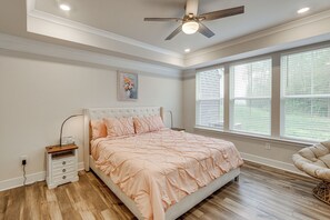 A bedroom with a bed, bedside table, nightstand, and a ceiling fan.