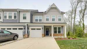 A two-story residential building with a garage, a driveway, and a well-maintained lawn.