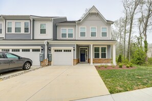 A two-story residential building with a garage, a driveway, and a well-maintained lawn.