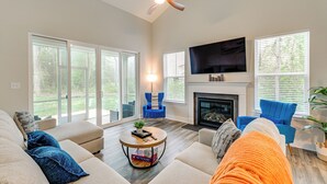 A living room with a fireplace, a television, and a ceiling fan.