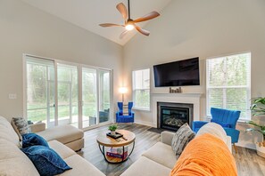 A living room with a fireplace, a television, and a ceiling fan.