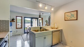 Cozinha com pia, armários e bancada. Uma janela oferece vista para o verde lá fora.