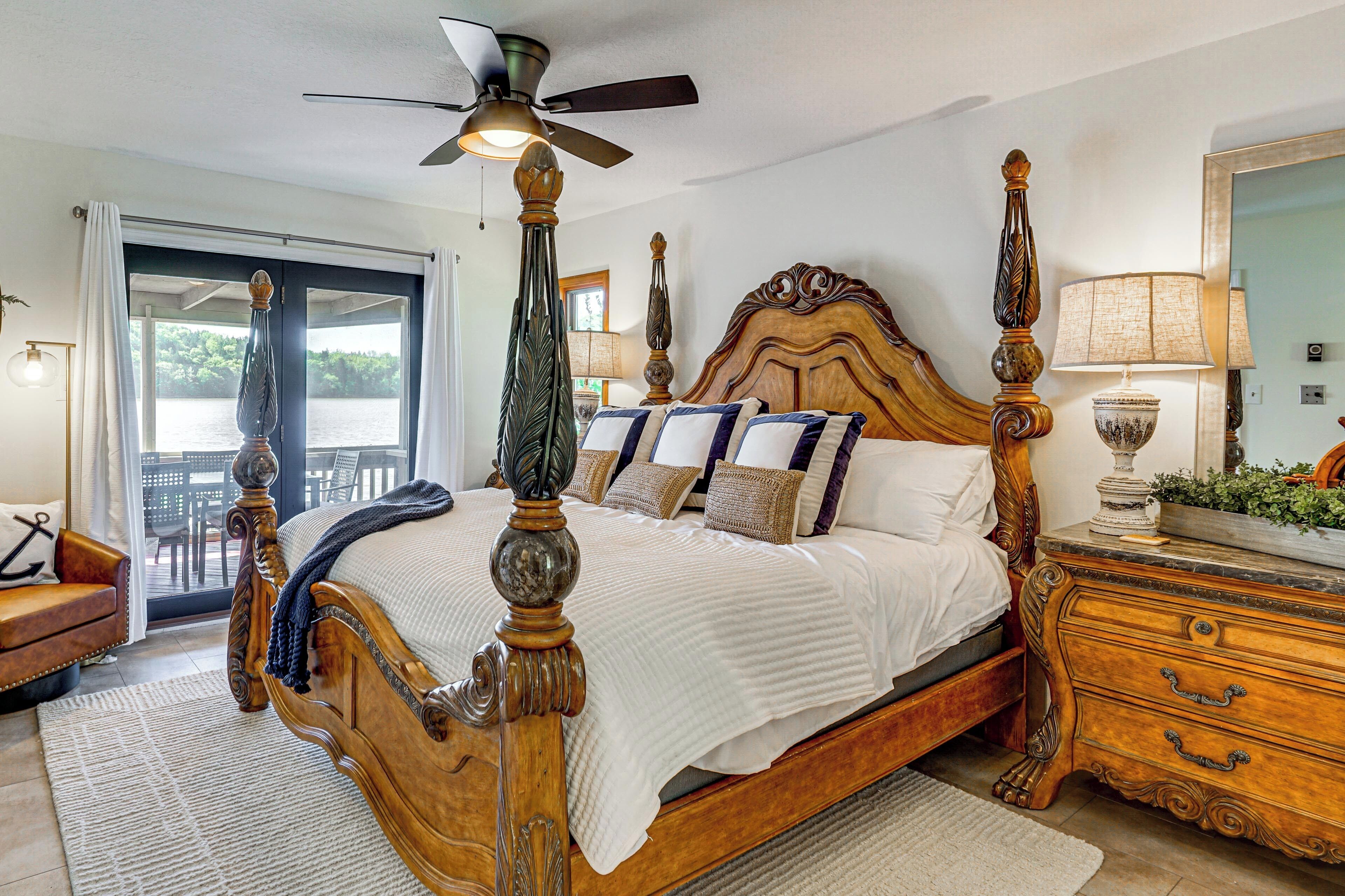 A four-poster bed with a ceiling fan, a wooden dresser, and a view of the outdoors through a sliding door.