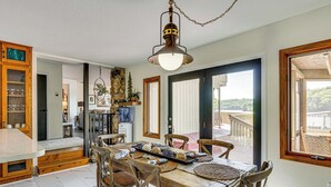 Uma sala de jantar com mesa de madeira, cadeiras e luminária pendente.