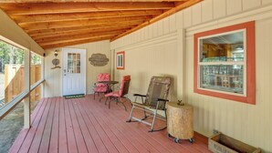 A wooden deck with chairs, a table, and a window with a view. - Deschutes Forest Basecamp! Oregon Cabin (La Pine)