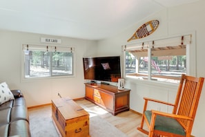 A living room with a television, a wooden cabinet, a sofa, and a chair.