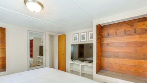 A bedroom with a bed, a TV, a wooden wall panel, and a mirror. - Deschutes Forest Basecamp! Oregon Cabin (La Pine)