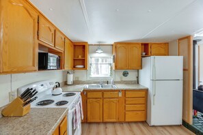 A kitchen with wooden cabinets, a white stove, a sink, and a refrigerator. - Deschutes Forest Basecamp! Oregon Cabin (La Pine)