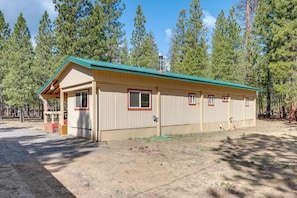 A single-story building with a green roof, a front porch, and a small deck area. - Deschutes Forest Basecamp! Oregon Cabin (La Pine)