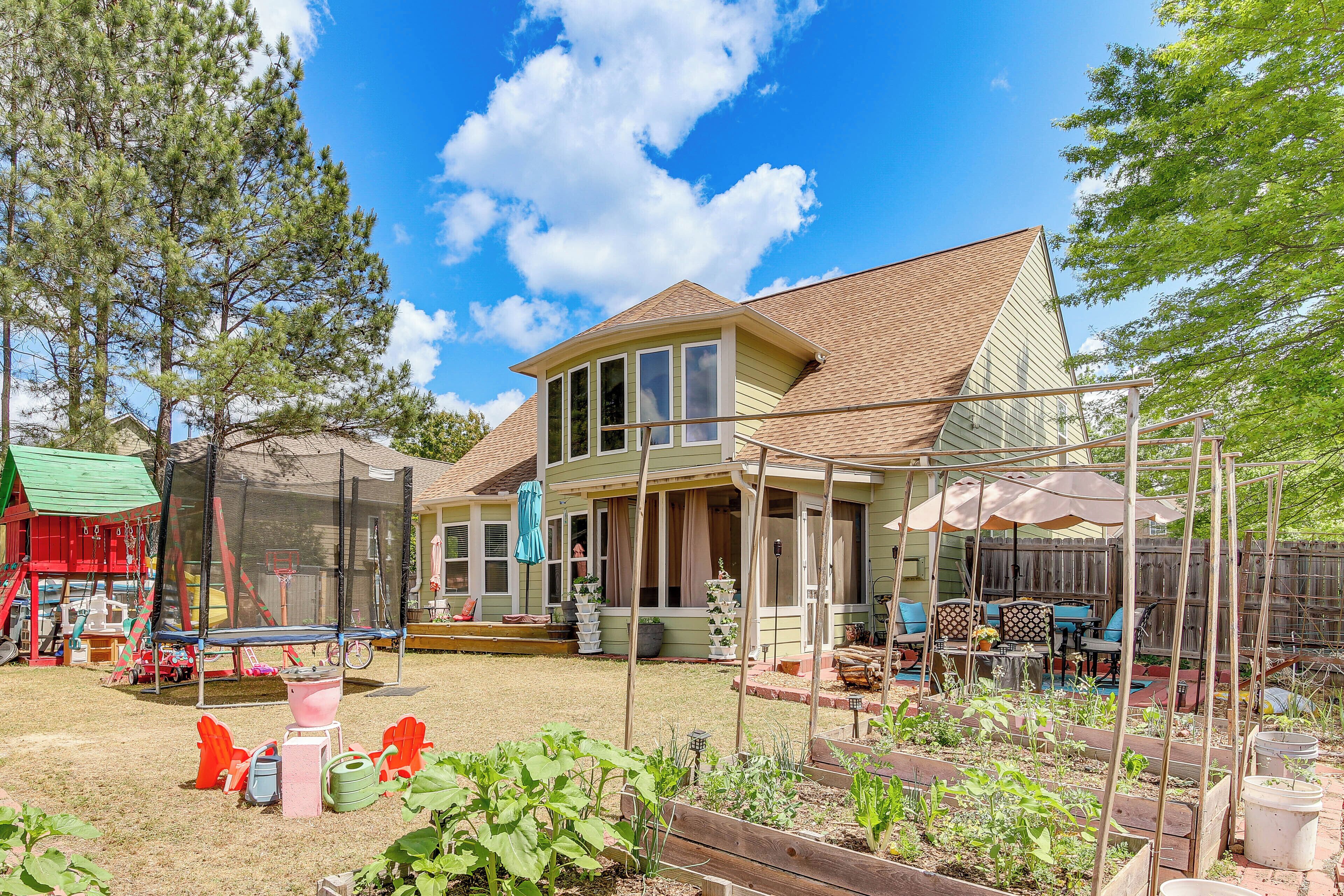 A two-story house with a covered patio, a fenced backyard, and a trampoline.