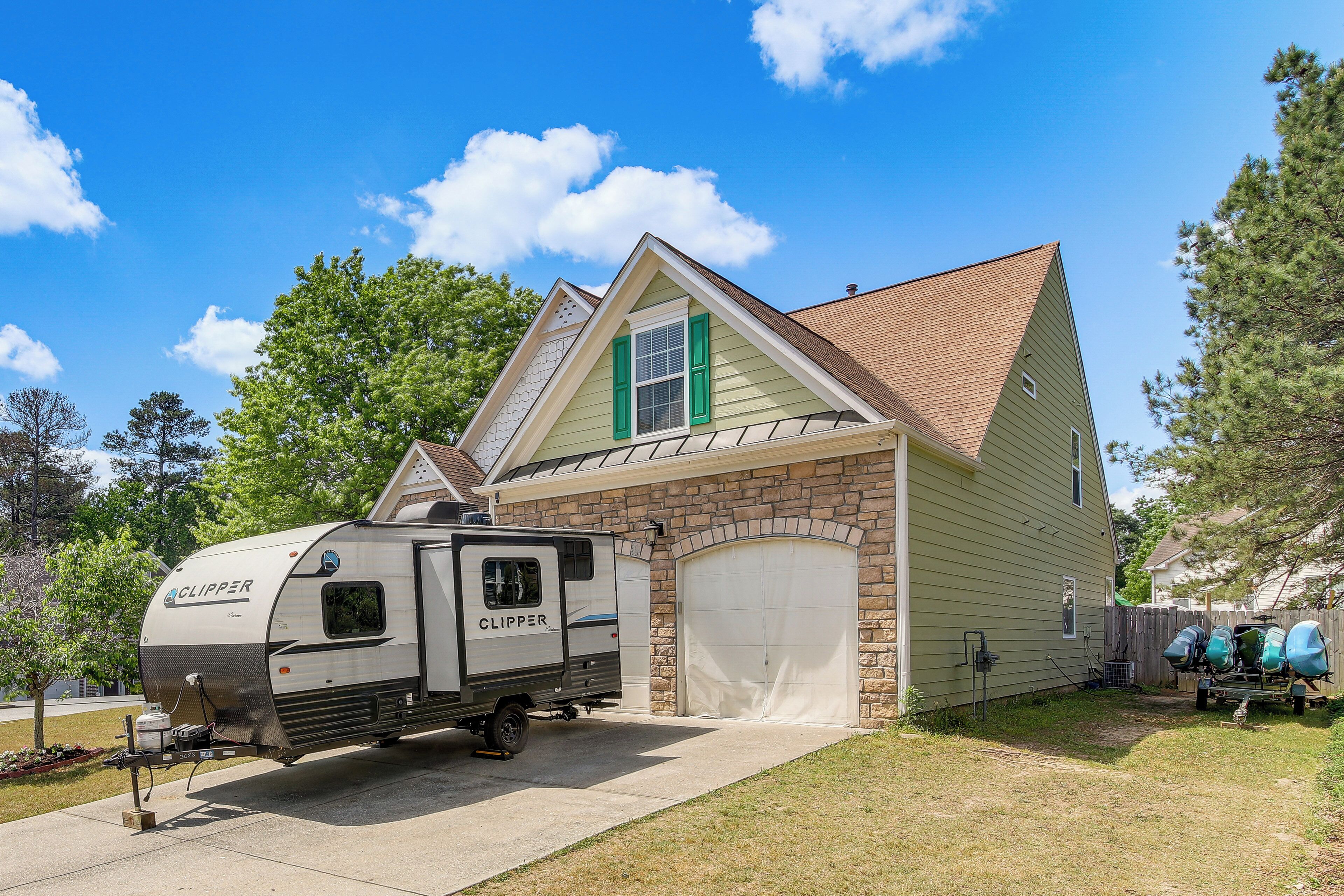 A single-story house with a garage, a camper parked in front, and a clear blue sky.