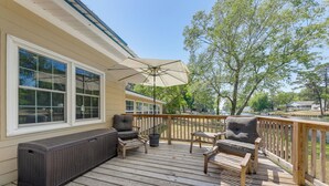 A wooden deck with outdoor seating, a large umbrella, and a view of a body of water.