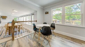 A spacious room with a wooden dining table and chairs, large windows, and a view of the outdoors.