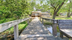 A wooden bridge leading to a building with a deck and a small water body nearby. - Waterfront Lake Marion Home w/ Dock: Fish & Boat! (Manning)