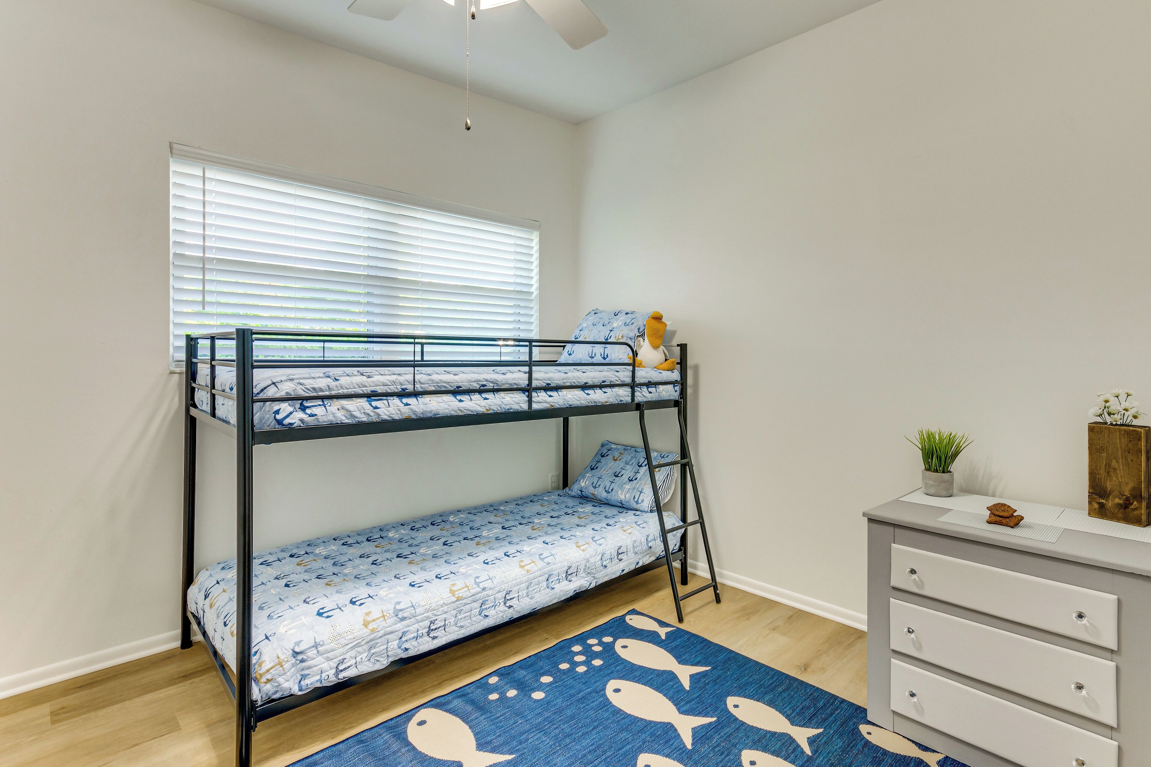 A bunk bed with a nautical theme, a dresser, and a rug with fish patterns.