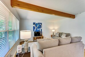 Un salon avec un canapé, un téléviseur, une lampe et un tableau au mur.