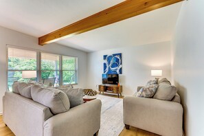 Un salon avec un canapé, une table basse, un téléviseur et un plafond avec une poutre en bois.