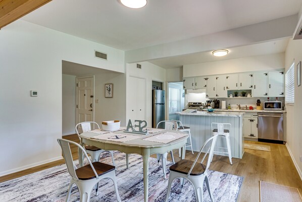 Un espace repas avec une table, des chaises et une cuisine en arrière-plan.