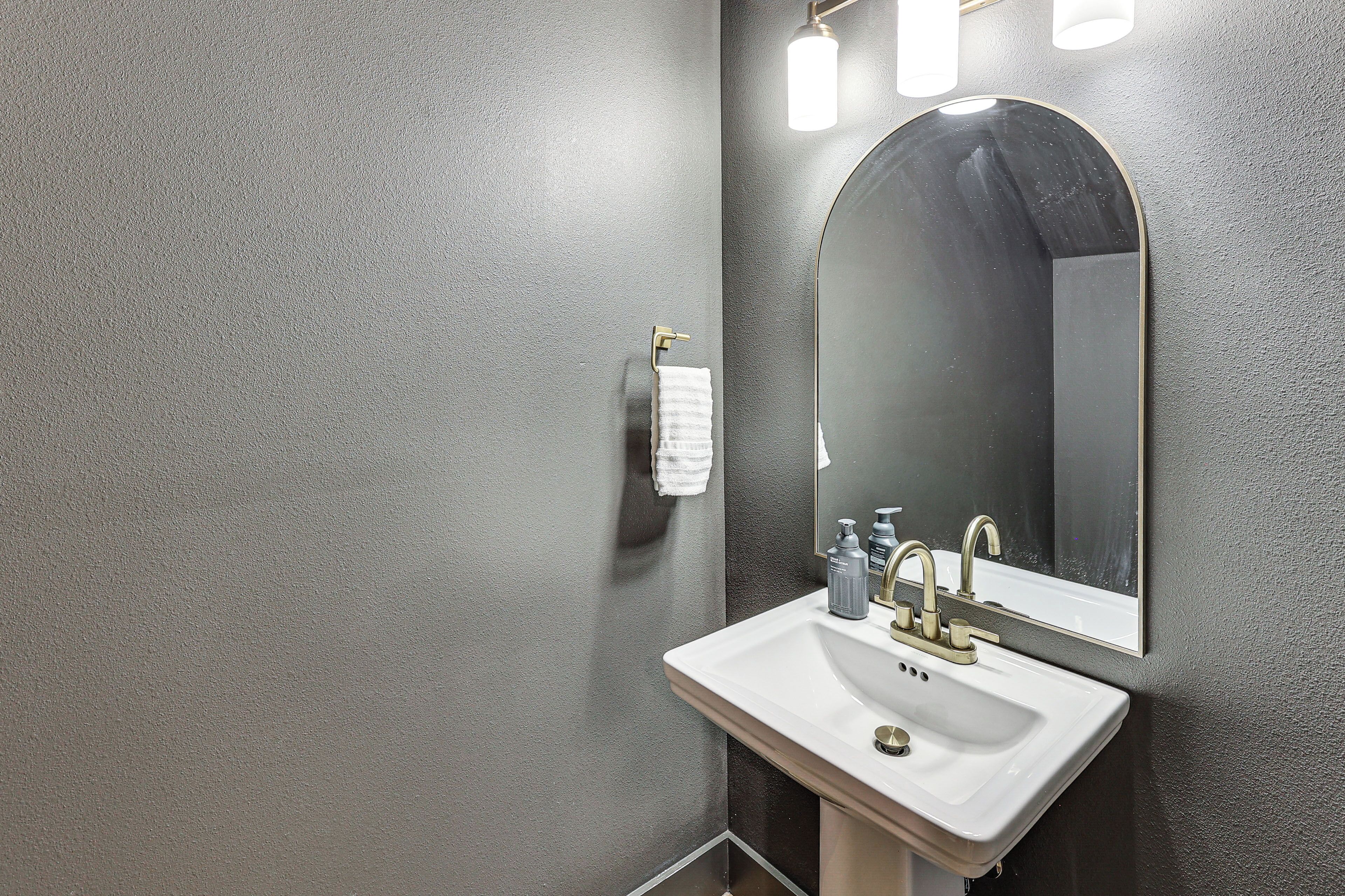 A bathroom with a white sink, a large mirror, and a towel rack.