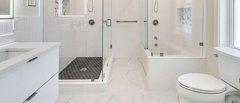 A modern bathroom with a glass-enclosed shower, a white toilet, and a sink with a mirror.