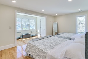 A hotel room with two beds, a large window, a radiator, and a door leading to an outdoor area.