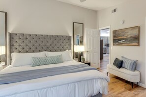 A bedroom with a tufted headboard, a bed with white bedding, a bedside table with a lamp, a bench with cushions, and a painting on the wall. - Hike, Work & Play! SLO Home: 2 Mi to Beaches (San Luis Obispo)