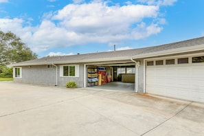 Ein eingeschossiges Gebäude mit Garage, überdachter Veranda und kleinem Außenbereich mit Pflanzen.