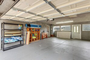 Eine Garage mit Betonboden, Metalldecke und einem Holzregal mit diversen Gegenständen.