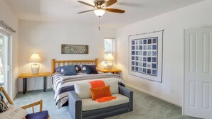A bedroom with a bed, a ceiling fan, a nightstand, a lamp, a chair, and a wall art piece. - Game Room & On-site Golf Course! Lake Almanor Home (Westwood)