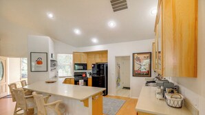 A modern kitchen with wooden cabinets, a central island with chairs, a refrigerator, and a microwave. - Game Room & On-site Golf Course! Lake Almanor Home (Westwood)
